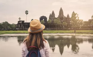 Ein Mädchen blickt auf die Tempelanlage Angkor Wat in Kambodscha, die im Hintergrund zu sehen ist.