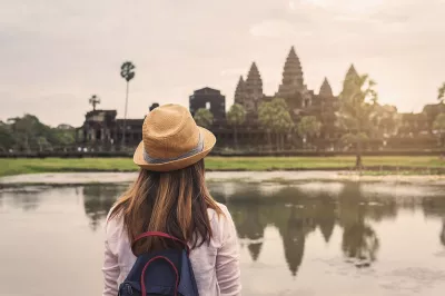 A girl looks at the Angkor Wat temple complex in Cambodia, which is visible in the background.